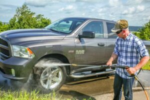 Man cleaning truck wheel wells with pressure washer rental